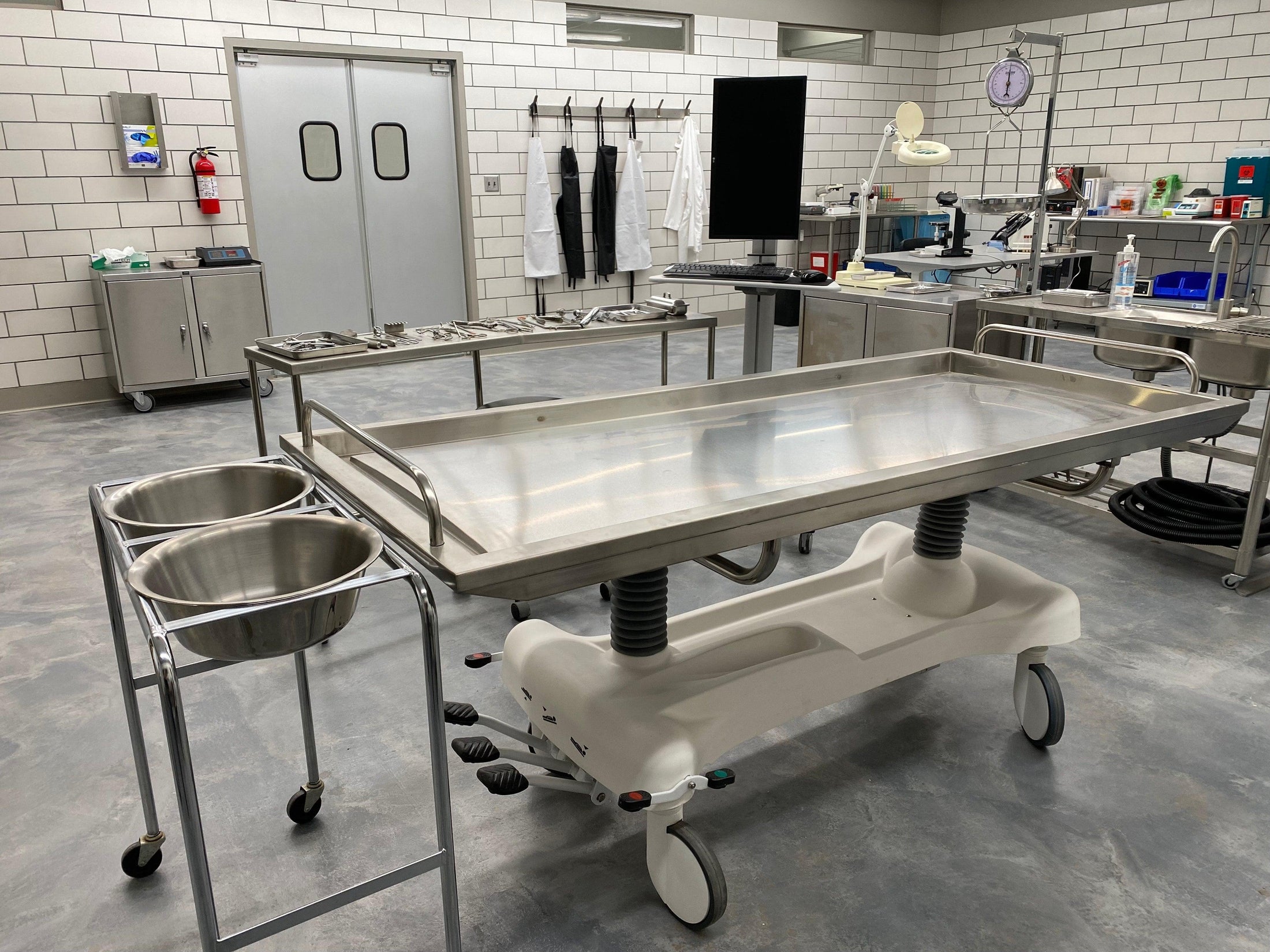 Mortuary cooler table and equipment in a professional autopsy room setting.